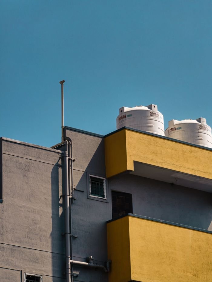 Close-up of a building facade with water tanks under clear blue sky.